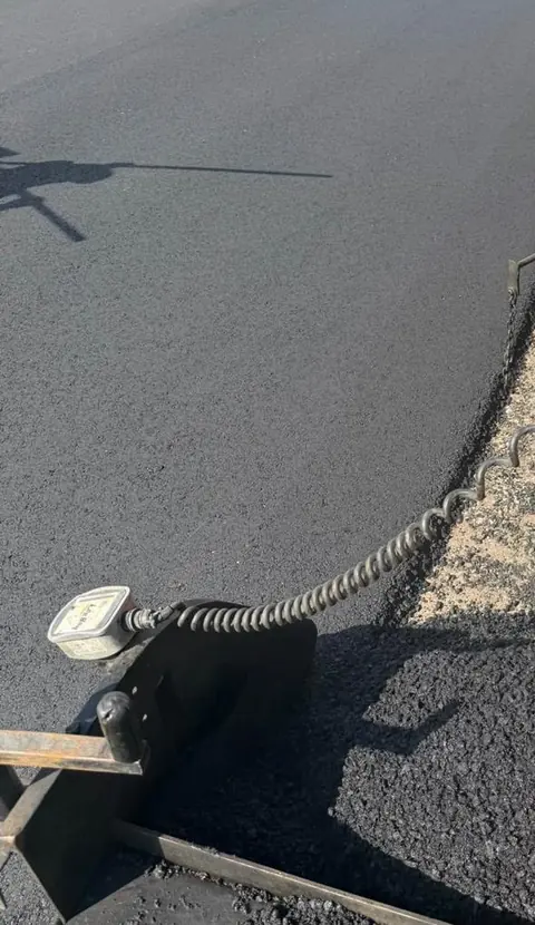 Close detail of fresh asphalt meeting an unfinished gravel edge